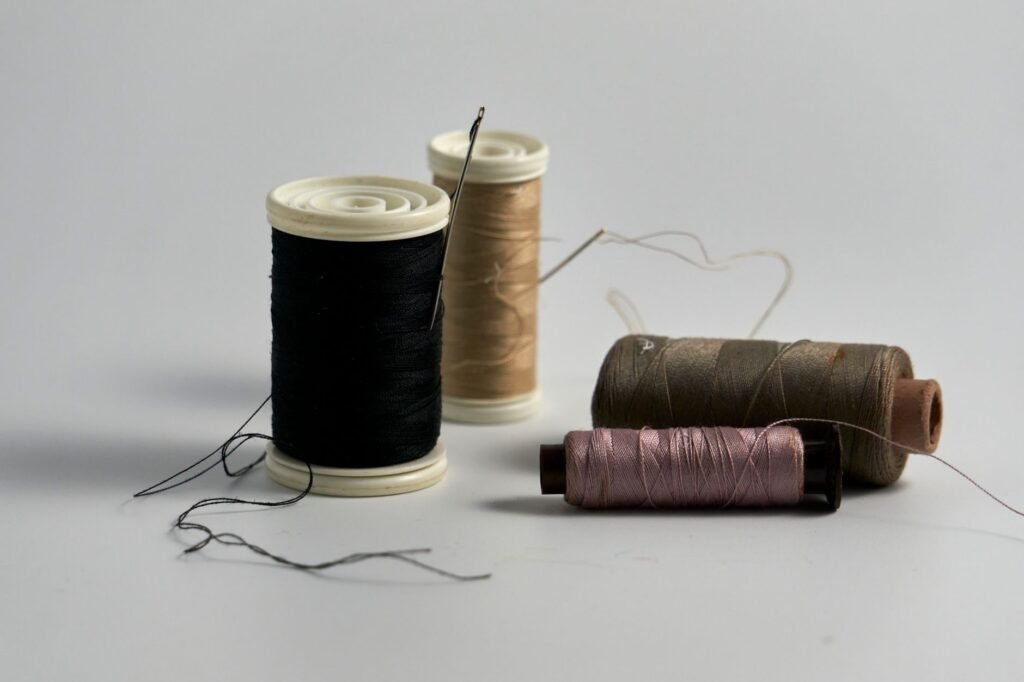 Carretes de hilo oscuro con una aguja de coser