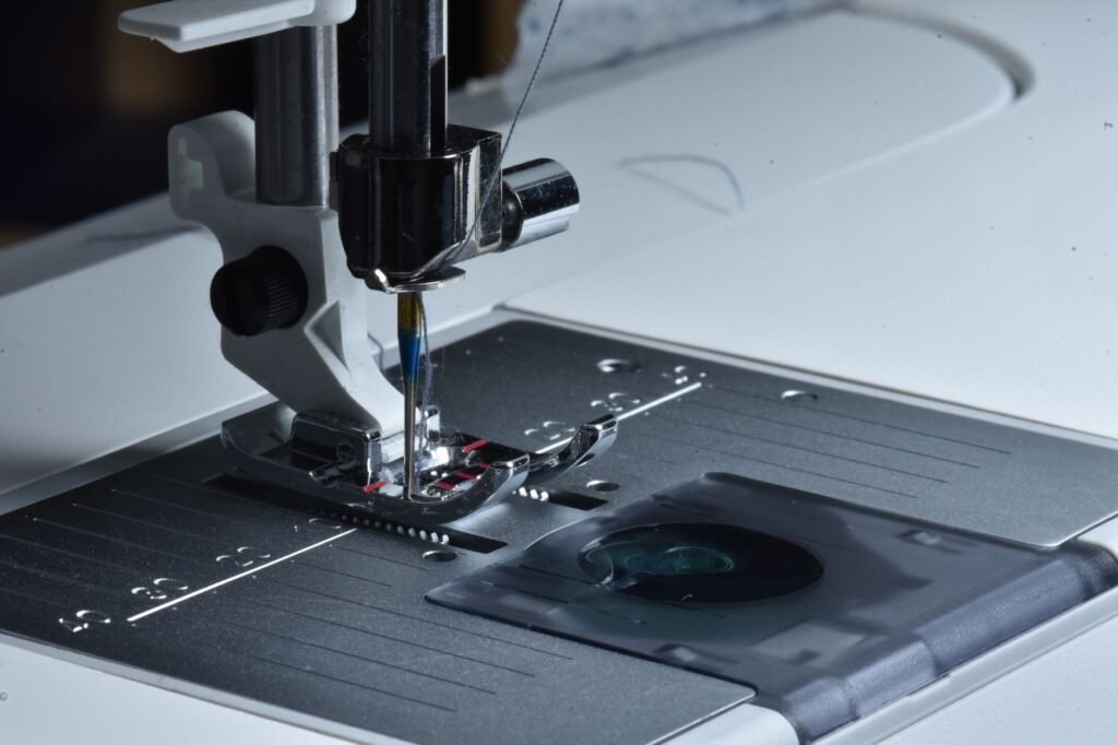 Aguja y prensatelas de una máquina de coser sobre la placa de aguja metálica