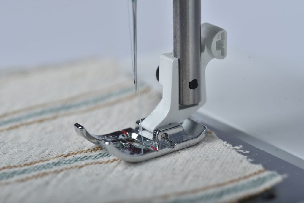 Prensatelas y aguja de una máquina de coser sobre una tela con rayas