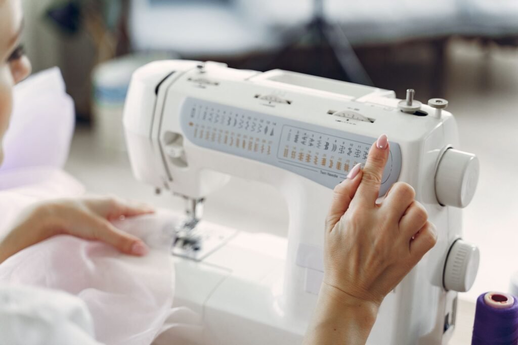 Una mano señala el panel de puntadas de una máquina de coser doméstica blanca