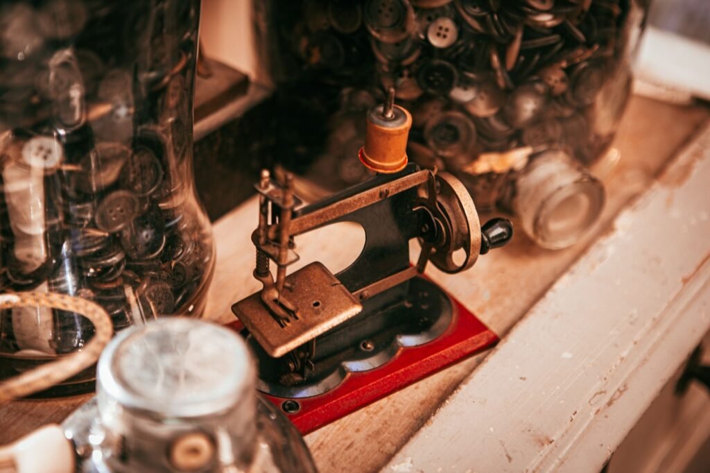 Pequeña máquina de coser antigua de metal sobre una mesa de madera