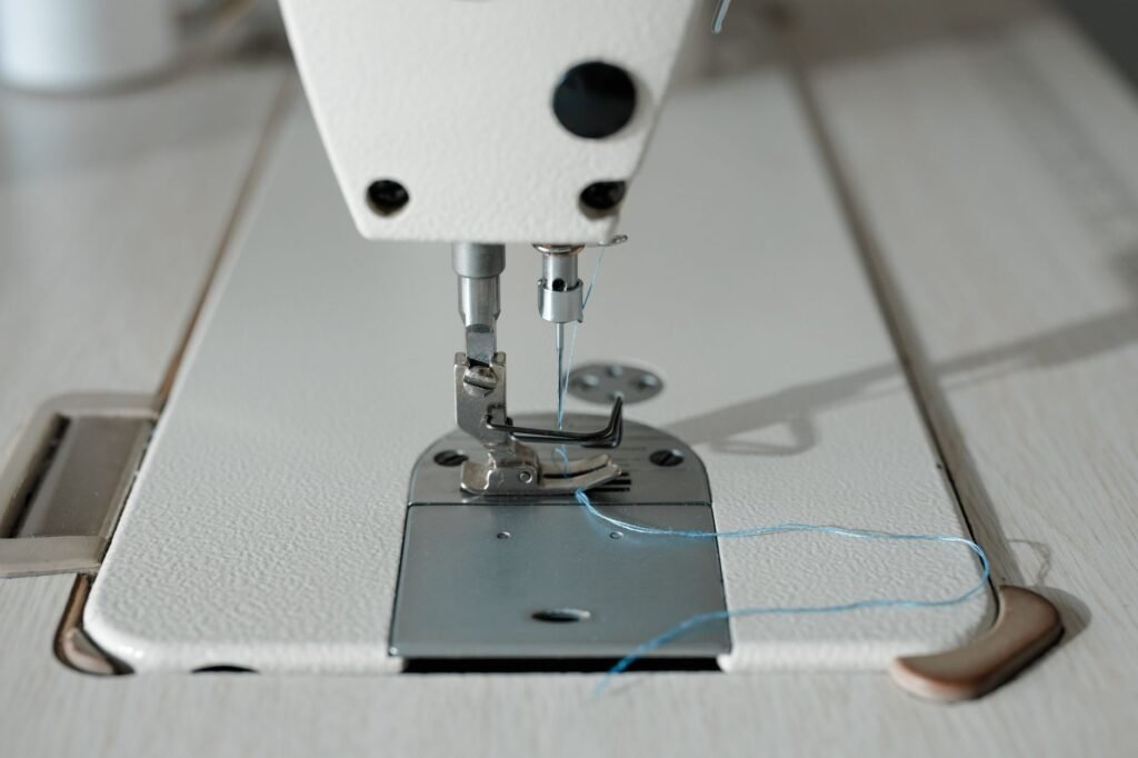 Aguja de una máquina de coser con hilo azul sobre una superficie clara