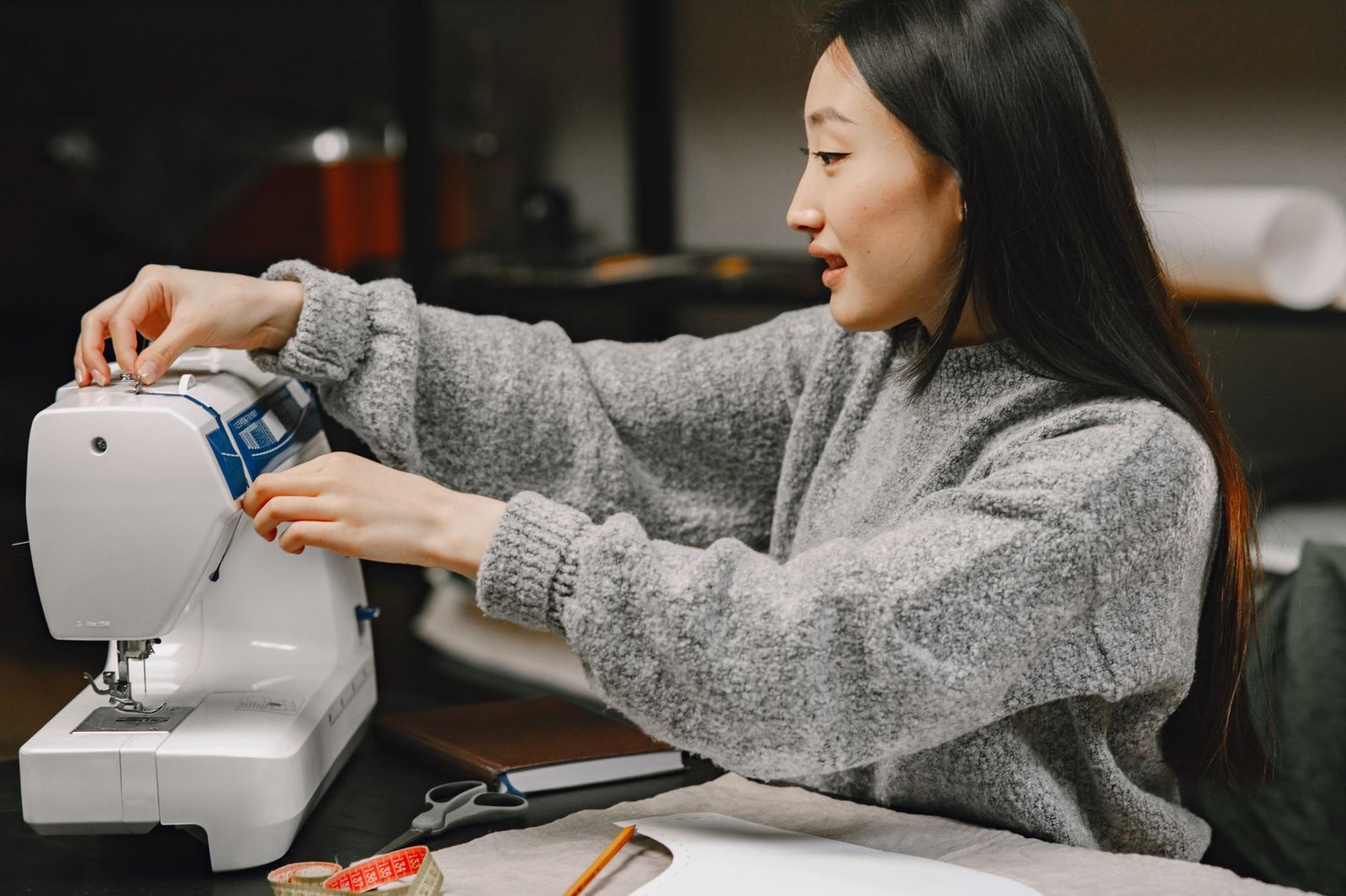 Mujer cosiendo con una máquina de coser doméstica en un espacio de trabajo luminoso